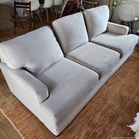 Front view of three-seat white fabric sofa with cushions