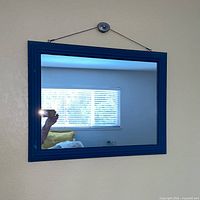Front view of blue wood framed wall mirror hanging on wall