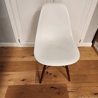 Front view of white molded plastic chair with wooden legs