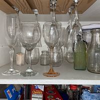 Wine glasses hanging and standing in cupboard with partial view of plastic containers