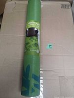 Rolled green Gaiam yoga mat in original wrap on cardboard box