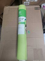 Rolled green yoga mat in wrap on box