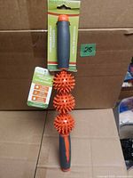 Full view of massager with tag showing three spiky balls and both handles