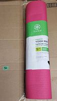 Front view of rolled pink yoga mat with Gaiam sleeve showing branding and 5 mm thickness