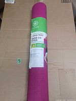 Rolled pink Gaiam yoga mat in original wrap