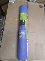 Rolled purple Gaiam yoga mat in original packaging