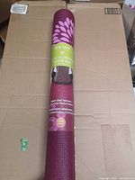 Rolled Gaiam purple floral yoga mat in packaging front view