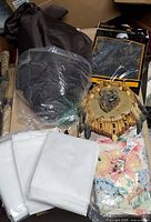 Overview of all items in lot including transfer paper, floral top, white linens, wall hanging, brown bag