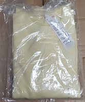 Front view of folded yellow Uniqlo kids sweatshirt sealed in plastic, tag visible