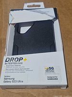 Front of opened OtterBox packaging displaying black Commuter Series Drop+ case