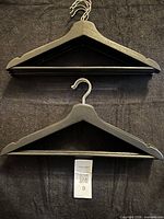 Front view of two black wooden hangers showing overall design and finish