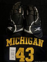 Front view of jersey with gloves placed on top showing Michigan lettering and number 43