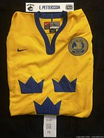 Folded yellow jersey showing three crowns emblem, Nike swoosh and Swedish Ice Hockey Federation patch