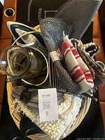 Basket showing iron, vase, textiles, glass, and utensils