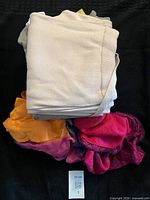 Stack of folded garments showing cardigan, grey top, bright scarf