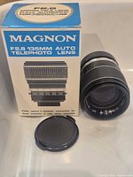 Lens standing beside box with front cap visible