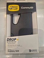 Front of retail package displaying OtterBox Commuter DROP+ black case for Galaxy S24