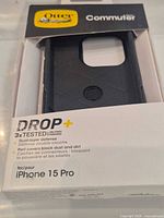 Front of sealed retail box showing OtterBox Commuter Series Drop+ case for iPhone 15 Pro
