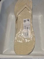 Top view of packaged beige flip-flop showing size and sole pattern