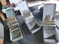 Three metal drill index boxes with bits displayed