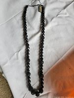 Full view of black beaded necklace with tag attached