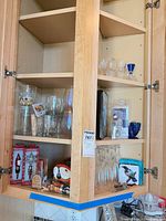 Open cabinet showing wine, cordial and other stemware plus boxed bar tools and accessories