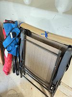 Stacked woven sling patio chairs, camp chairs in bags, rolled beach mat