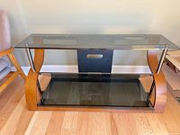 Front view of Bell'O media stand showing glass shelves, wood sides, metal posts and back panel