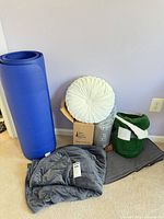 Group shot of all items including weighted blanket, blue foam mat, boxed blanket, pillow, green throw