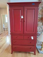 Front full view of red painted cabinet with doors closed and drawers visible