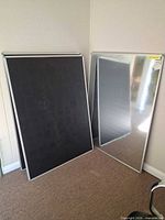 Two boards leaning showing black chalkboard and metallic sides
