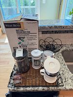Lot overview showing boxed West Bend coffee urn and additional coffee accessories on tray