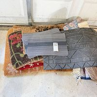 stack of various mats showing grey striped mat, floral coir mat, rubber mat underneath