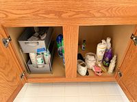 Open cabinet showing plastic drawers, paper cups, cleaners and personal-care bottles