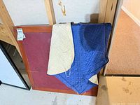 Wood folding table leaning against wall with quilted cover draped over