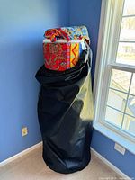 Rolled futon mattress inside black storage bag showing colourful cover
