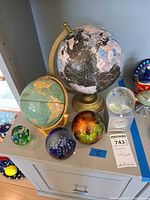 Overview showing two globes, Stauer clock with globe, and two paperweights