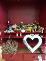 Overall view of assorted Easter décor on red cabinet shelf including mushrooms, rabbits, heart frame, twig basket