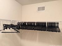Full closet rod showing large quantity of black plastic hangers