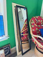 Two framed full-length mirrors, black and cream frames, leaning against wall