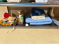 Shelf with moving blankets, tarp, caddy of tools and basket of chemicals