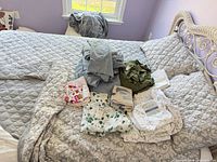 Bed showing grey comforter, shams and assorted folded sheet sets
