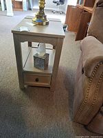 Full view of side table beside couch showing top, shelf, and drawer front