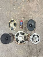 Group shot of five speaker drivers showing both round and oval units with wiring and transformers
