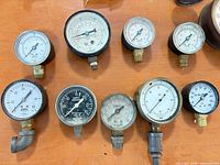Front view of nine smaller pressure gauges showing dial ranges and connection types