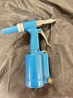 Right side view of blue pneumatic rivet tool