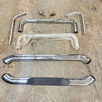 All components laid out: chrome side step bar, two curved brackets, mounting hardware