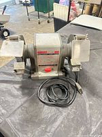 Front view of Craftsman bench grinder showing overall condition, eye shields, tool rests, and power cord
