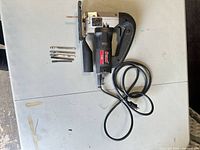 Top view of jig saw with coiled cord and blades