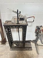 Full view of pipe bender mounted on steel stand showing manual lever and hydraulic hose